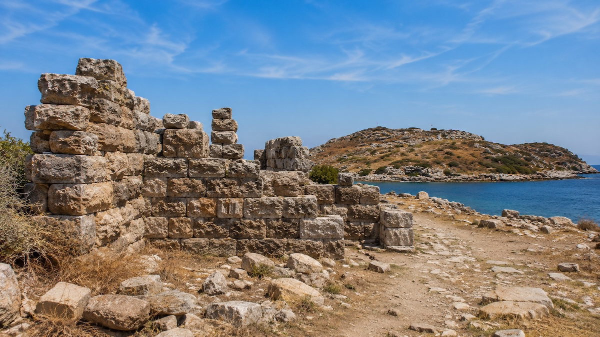 Bodrum'daki Myndos Antik Kenti'nde tarihi taş kalıntıları, antik surlar ve Ege Denizi manzarasını yansıtan arkeolojik alan.